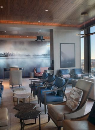 A modern lounge area with numerous chairs, large windows with a scenic view, and a mural of a city skyline on one wall ends the sentence.